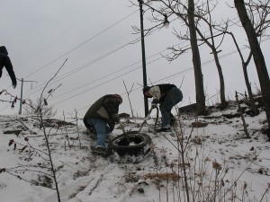 Conor and Chris drag a heavy tire up the steep slope from the river's shoreline